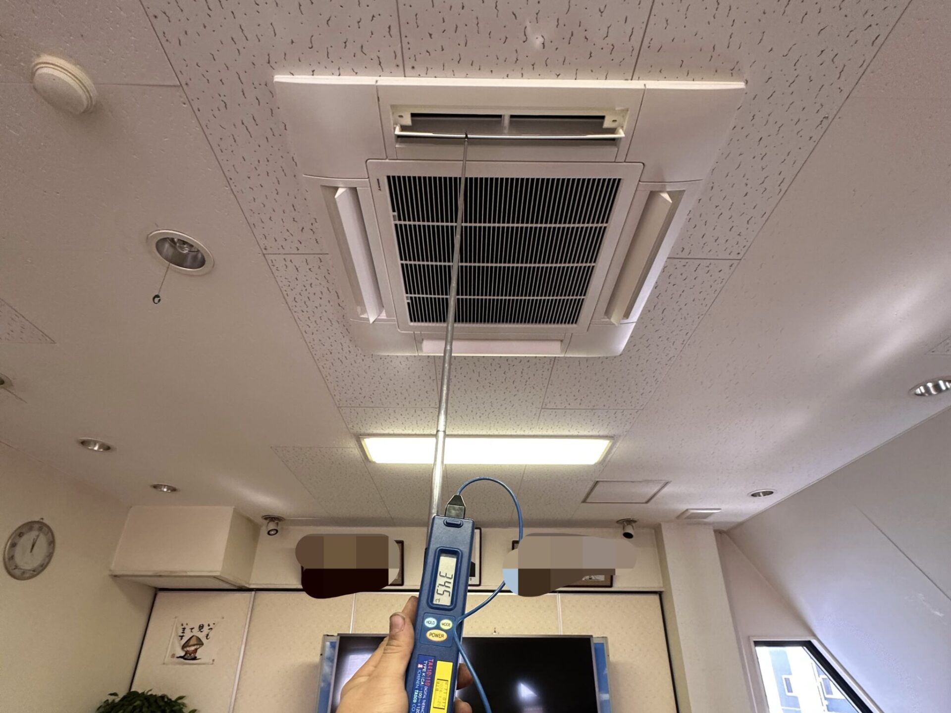 松山市で施工した天井カセット型エアコン更新後の吹き出し温度測定の様子
