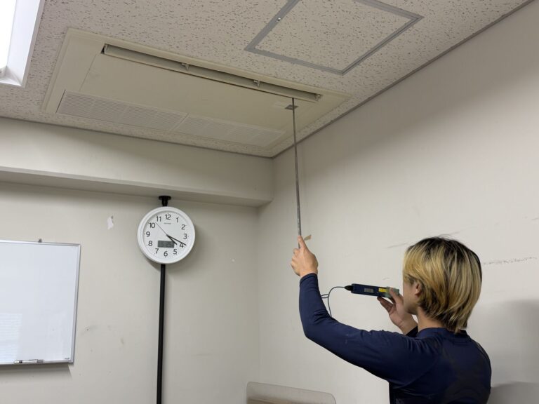 松山市の大学施設で業務用エアコン修理後に試運転と吹出口温度測定を行う様子