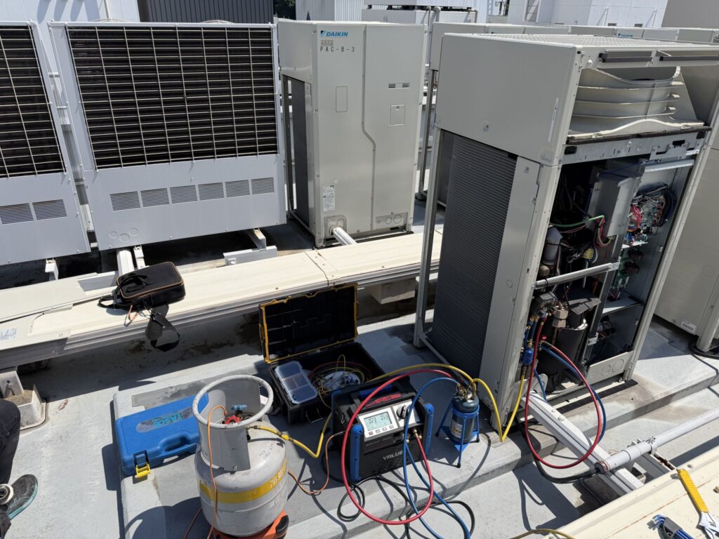 松山市で業務用エアコンのフロンガス回収を実施している様子。回収機・回収ボンベ・マニホールドゲージを使用し、フロン排出抑制法に基づいて冷媒ガスを適正回収しています。