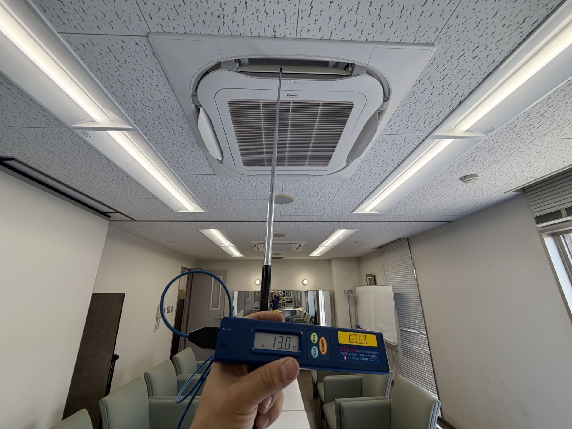 大学控え室の業務用エアコン更新工事完了後に吹出口温度13.0℃を確認する試運転の様子
